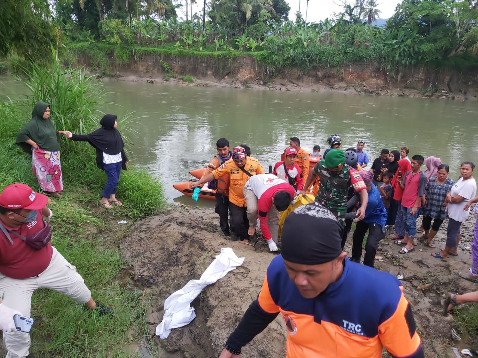 Babinsa Koramil 05/Lubuak Alung bersama warga Evakuasi korban Hanyut di Sungai Bukik ujung guguak (Poskota.net/Dok Ist)