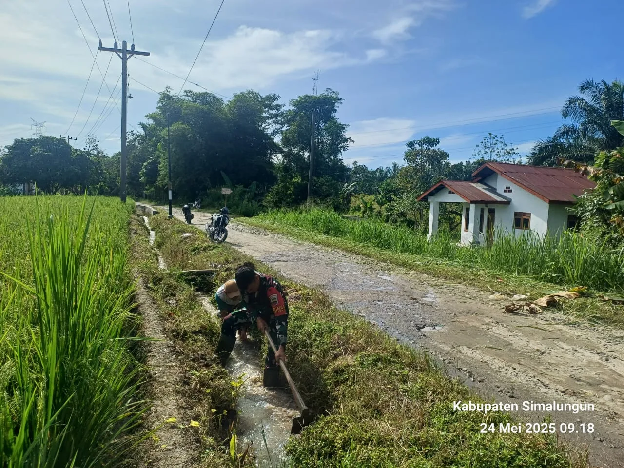 Babinsa Koramil 09/Tiga Balata Bantu Warga Bersihkan Irigasi Persawahan di Tomuan