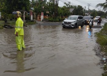 Hujan Deras Genangi Jalan KM 35! Dua Personil Polsek Perdagangan Siaga di Tengah Banjir Atur Lalin